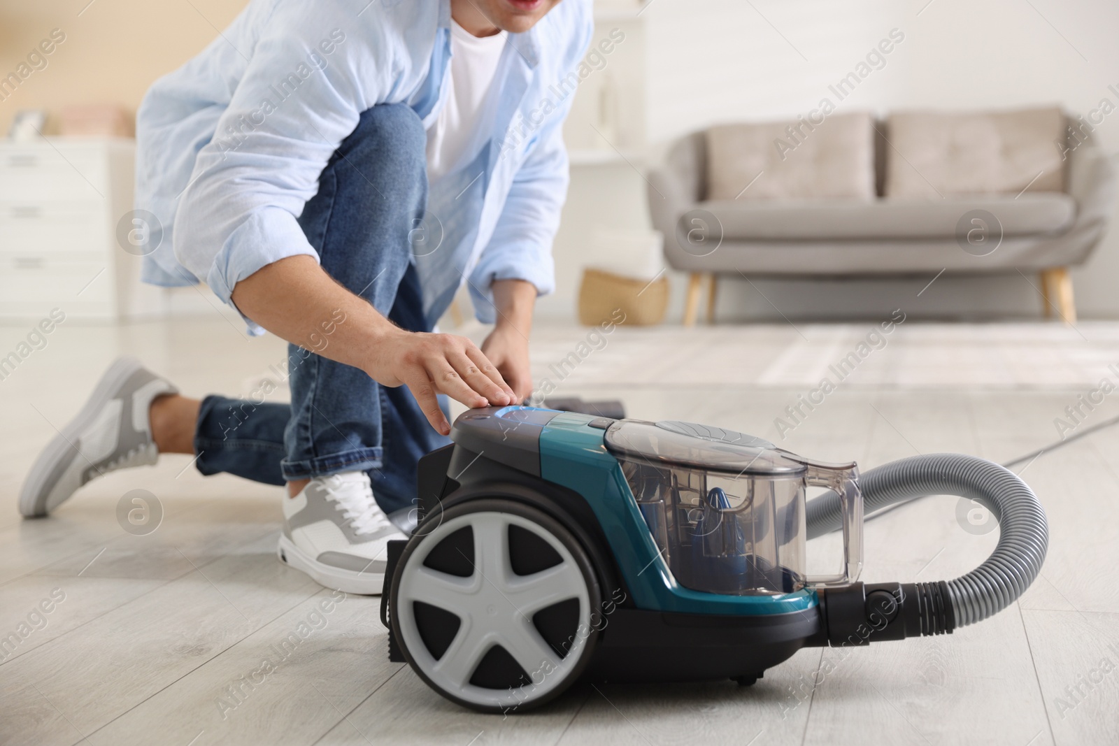 Man turning on vacuum cleaner at home, closeup Photo of Man turning on vacuum cleaner at home, closeup