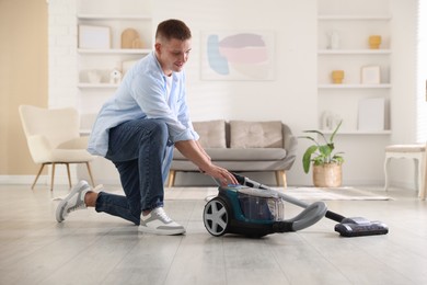 Photo of Man turning on vacuum cleaner at home