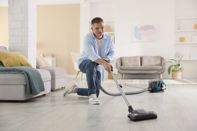 Photo of Man cleaning floor with vacuum cleaner at home