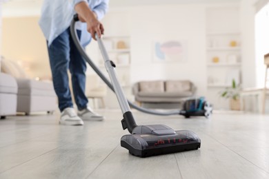 Photo of Man cleaning floor with vacuum cleaner at home, closeup