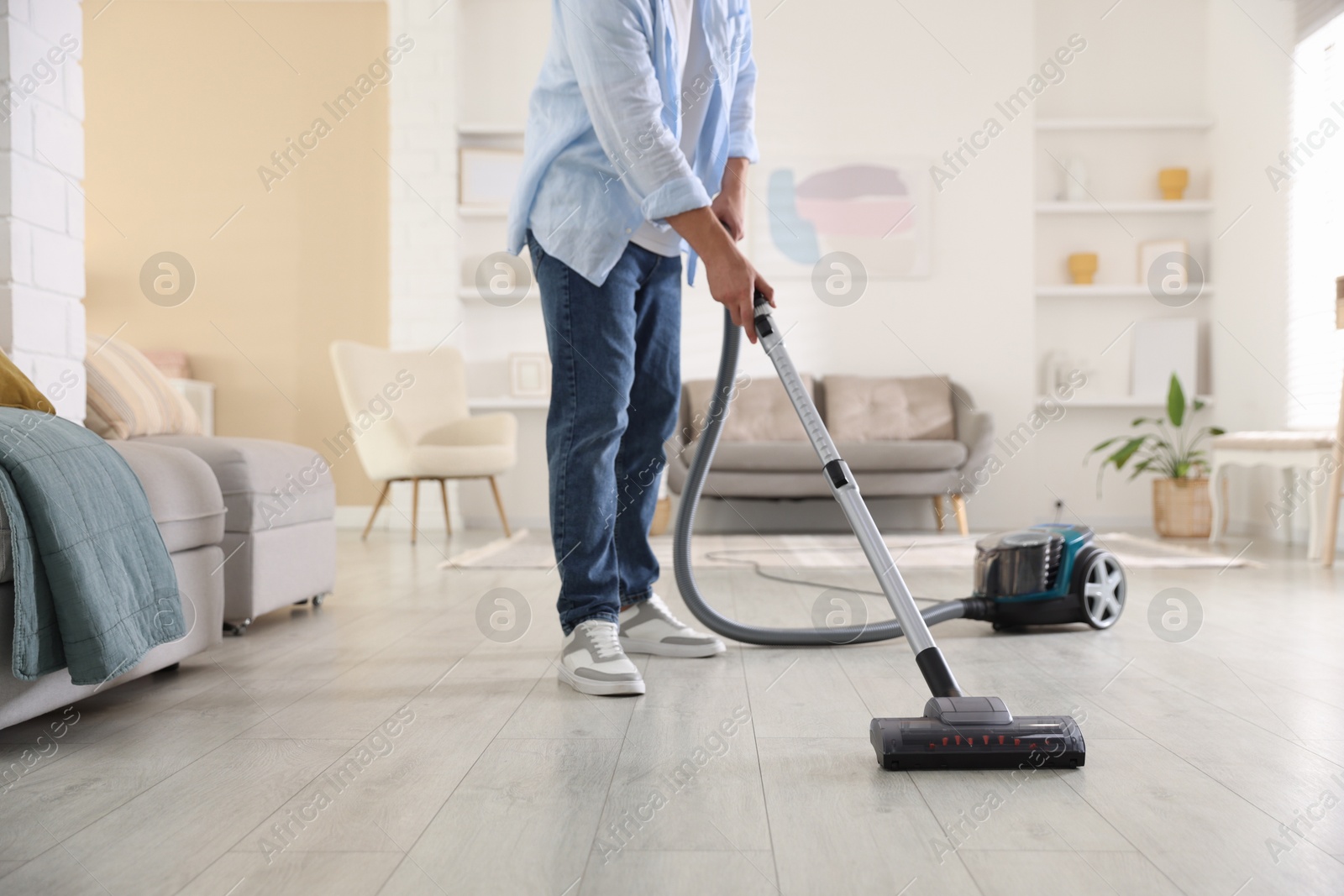 Man cleaning floor with vacuum cleaner at home, closeup Photo of Man cleaning floor with vacuum cleaner at home, closeup