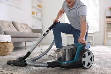 Photo of Man turning on vacuum cleaner at home, closeup