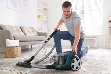 Photo of Man turning on vacuum cleaner at home