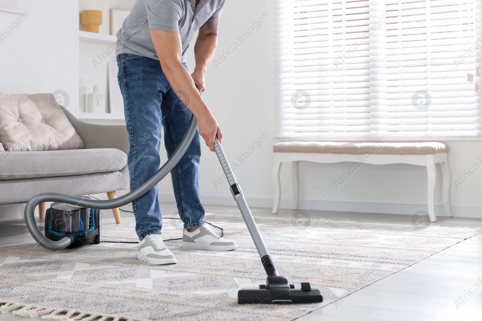 Man cleaning carpet with vacuum cleaner at home, closeup Photo of Man cleaning carpet with vacuum cleaner at home, closeup
