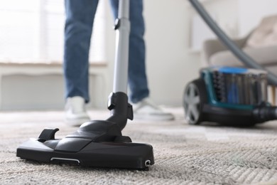 Photo of Man cleaning carpet with vacuum cleaner at home, closeup
