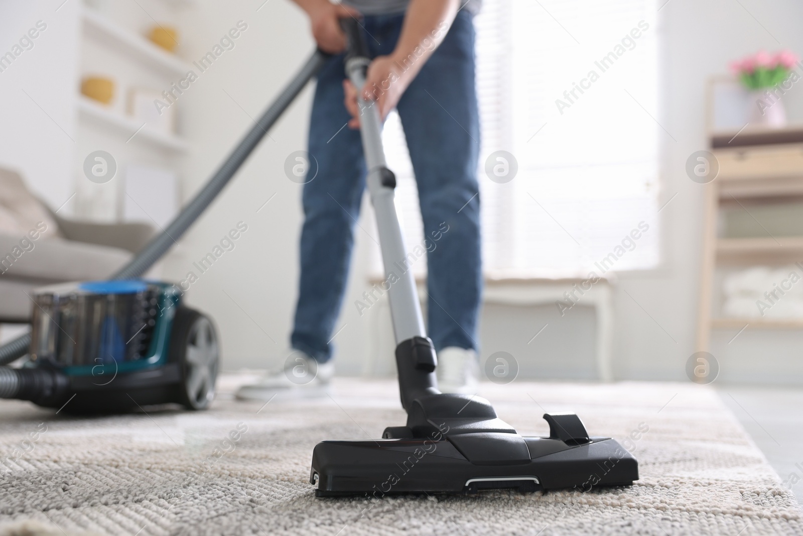 Man cleaning carpet with vacuum cleaner at home, closeup Photo of Man cleaning carpet with vacuum cleaner at home, closeup