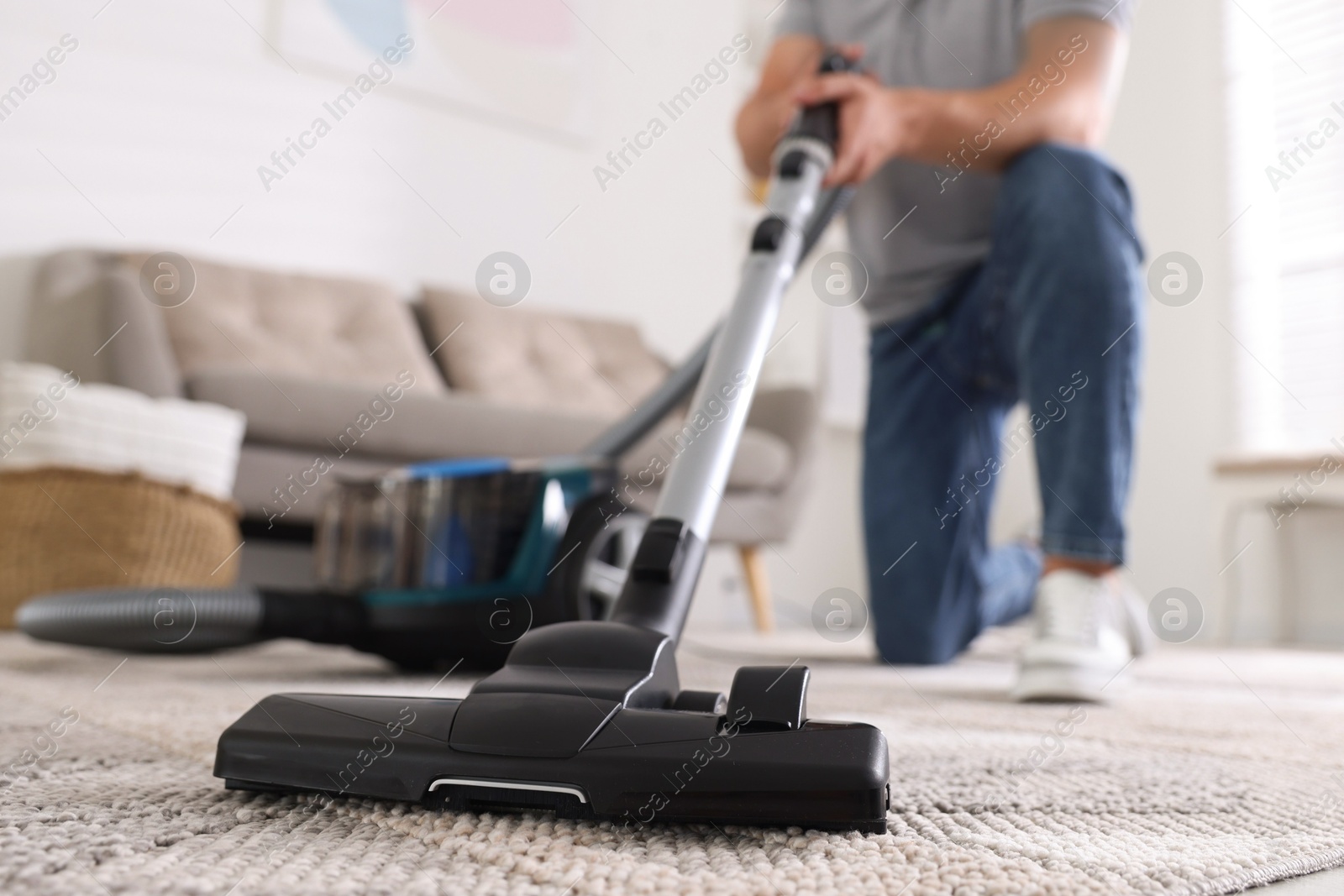 Man cleaning carpet with vacuum cleaner at home, closeup Photo of Man cleaning carpet with vacuum cleaner at home, closeup