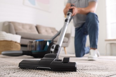 Photo of Man cleaning carpet with vacuum cleaner at home, closeup
