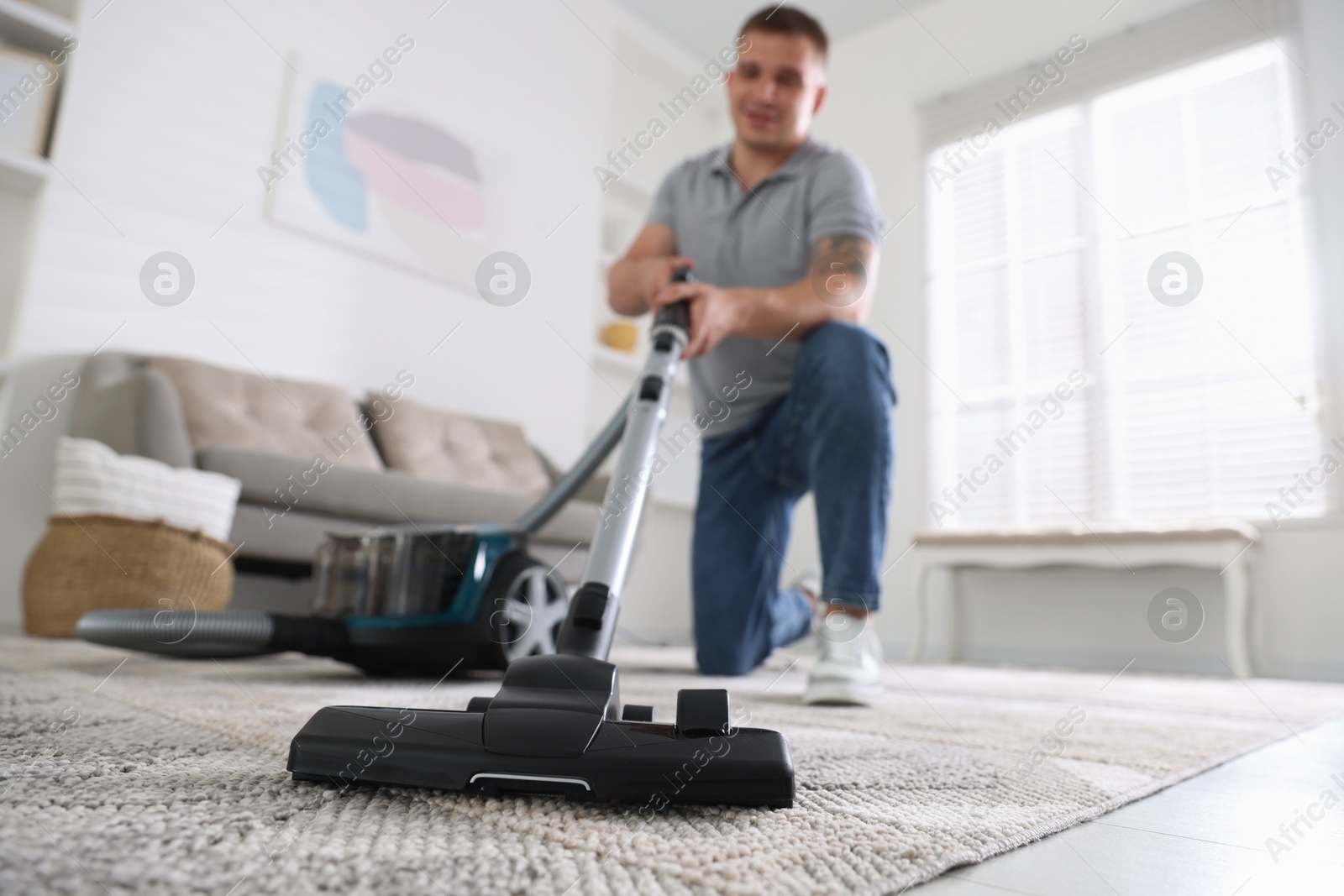 Man cleaning carpet with vacuum cleaner at home, low angle view Photo of Man cleaning carpet with vacuum cleaner at home, low angle view