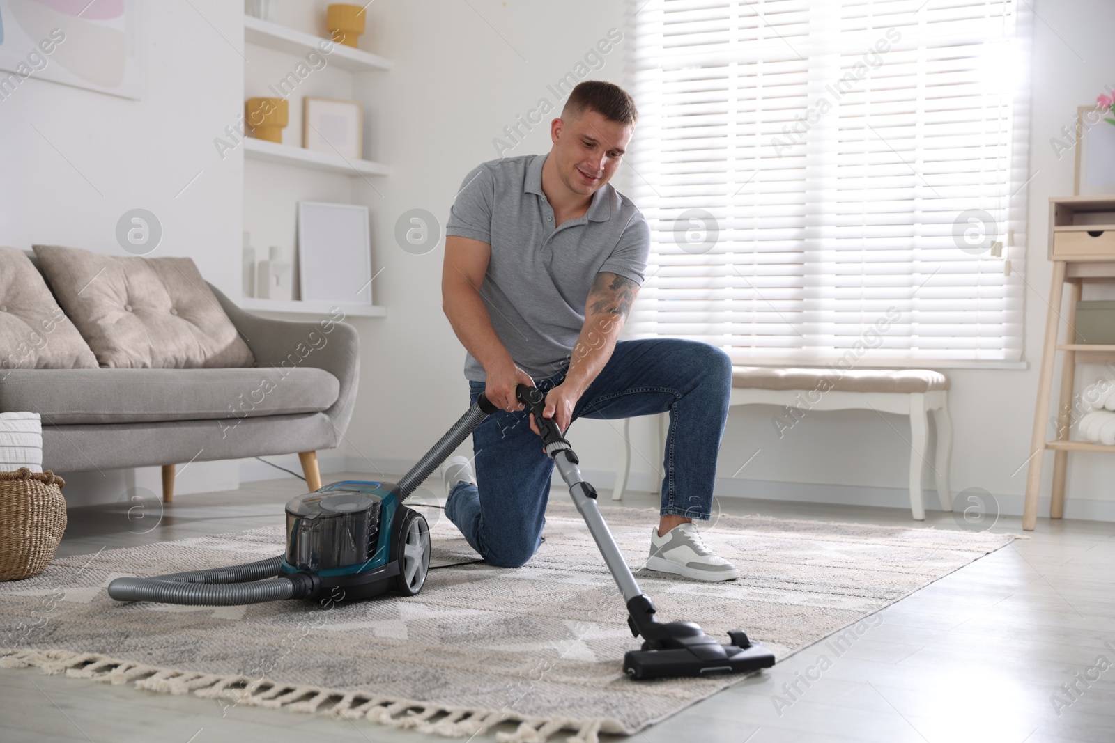 Man cleaning carpet with vacuum cleaner at home Photo of Man cleaning carpet with vacuum cleaner at home