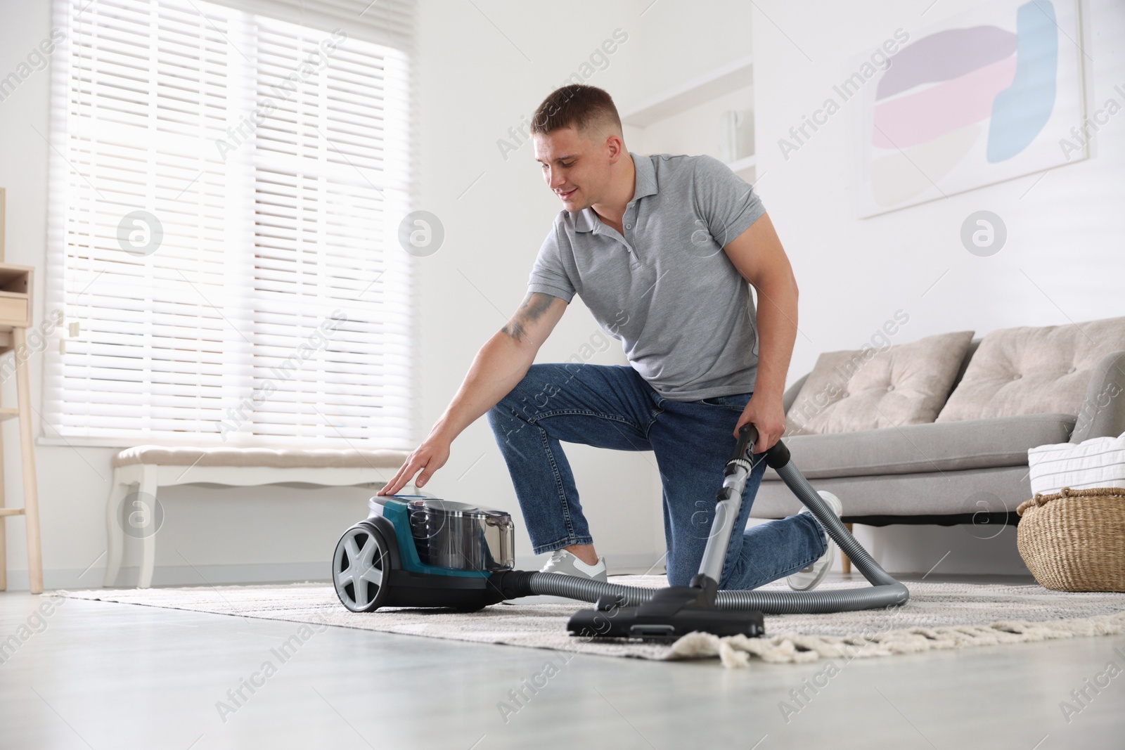 Man turning on vacuum cleaner at home Photo of Man turning on vacuum cleaner at home