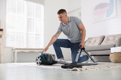 Photo of Man turning on vacuum cleaner at home