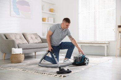 Photo of Man turning on vacuum cleaner at home
