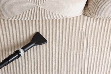 Photo of One vacuum cleaner nozzle on sofa, top view. Space for text