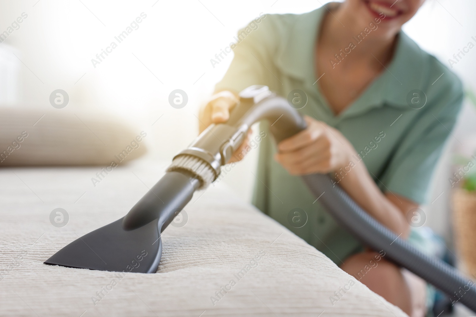 Woman cleaning sofa with vacuum cleaner at home, closeup Photo of Woman cleaning sofa with vacuum cleaner at home, closeup