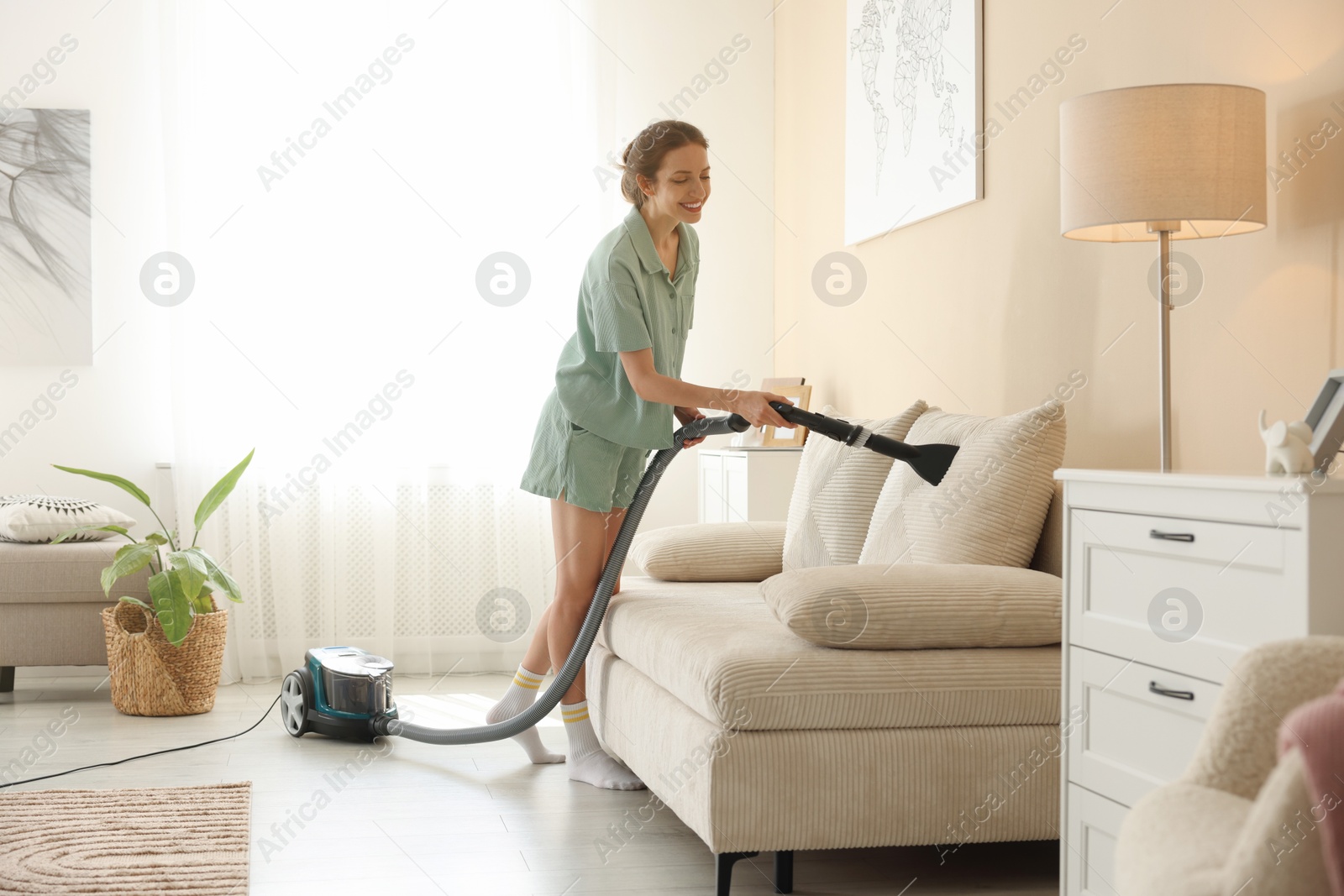 Woman cleaning sofa with vacuum cleaner at home Photo of Woman cleaning sofa with vacuum cleaner at home