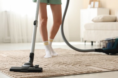 Photo of Woman cleaning carpet with vacuum cleaner at home, closeup