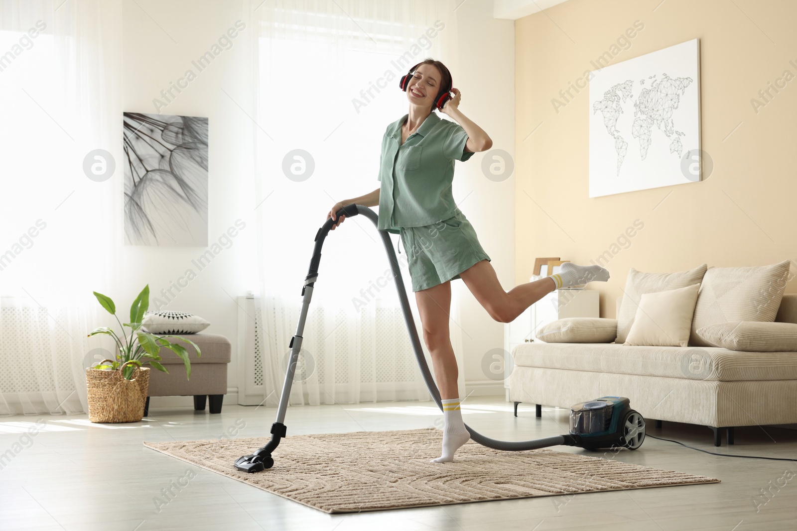 Woman in headphones cleaning carpet with vacuum cleaner at home Photo of Woman in headphones cleaning carpet with vacuum cleaner at home