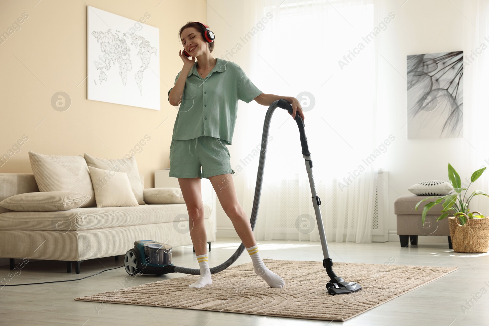 Woman in headphones cleaning carpet with vacuum cleaner at home Photo of Woman in headphones cleaning carpet with vacuum cleaner at home
