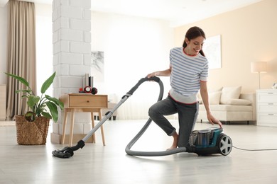 Photo of Woman cleaning floor with vacuum cleaner at home