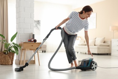 Photo of Woman cleaning floor with vacuum cleaner at home