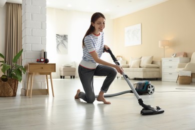 Photo of Woman cleaning floor with vacuum cleaner at home