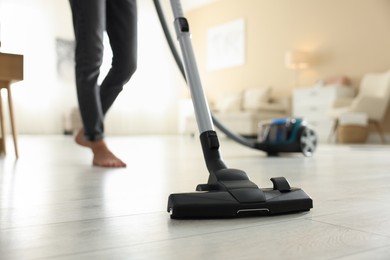 Photo of Woman cleaning floor with vacuum cleaner at home, closeup
