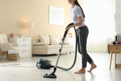 Photo of Woman cleaning floor with vacuum cleaner at home, closeup