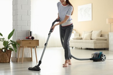 Photo of Woman cleaning floor with vacuum cleaner at home, closeup