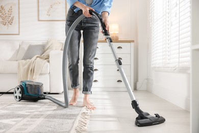 Photo of Woman cleaning floor with vacuum cleaner at home, closeup