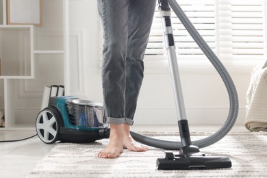 Photo of Woman cleaning carpet with vacuum cleaner at home, closeup