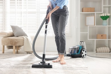 Photo of Woman cleaning carpet with vacuum cleaner at home, closeup