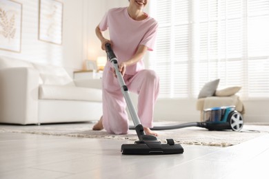 Photo of Woman cleaning floor with vacuum cleaner at home, closeup