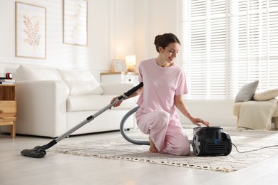 Photo of Woman cleaning floor with vacuum cleaner at home