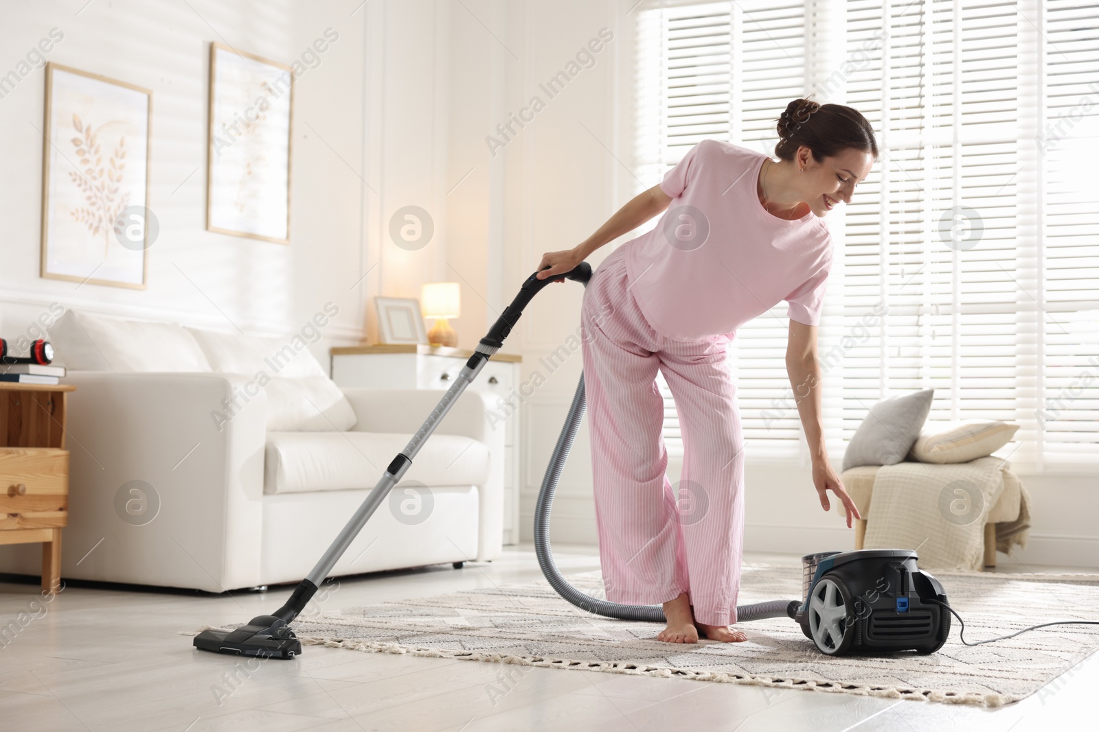 Woman cleaning floor with vacuum cleaner at home Photo of Woman cleaning floor with vacuum cleaner at home