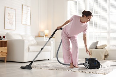 Photo of Woman cleaning floor with vacuum cleaner at home