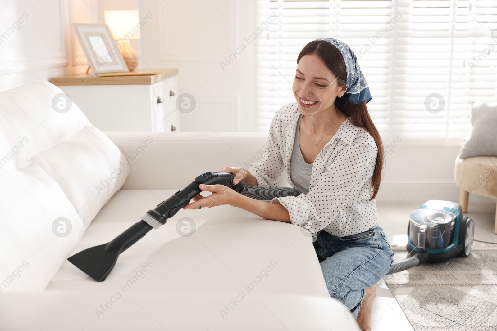 Woman cleaning sofa with vacuum cleaner at home Photo of Woman cleaning sofa with vacuum cleaner at home