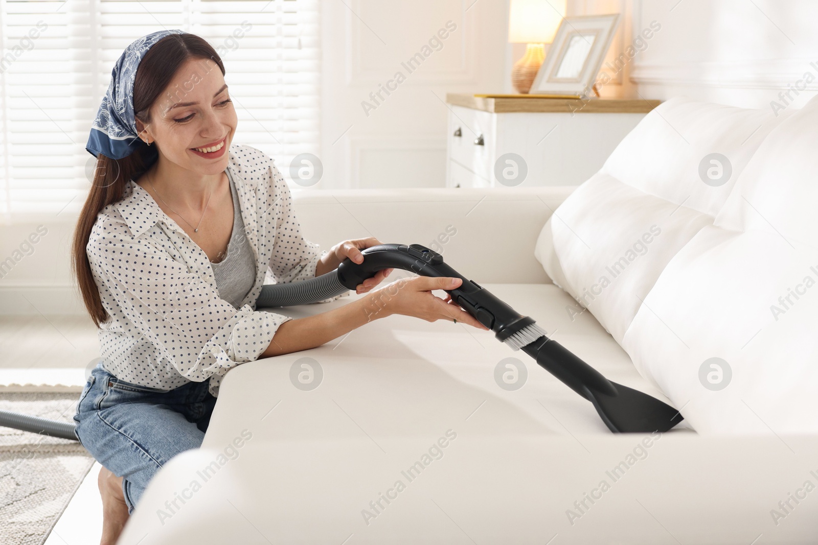 Woman cleaning sofa with vacuum cleaner at home Photo of Woman cleaning sofa with vacuum cleaner at home