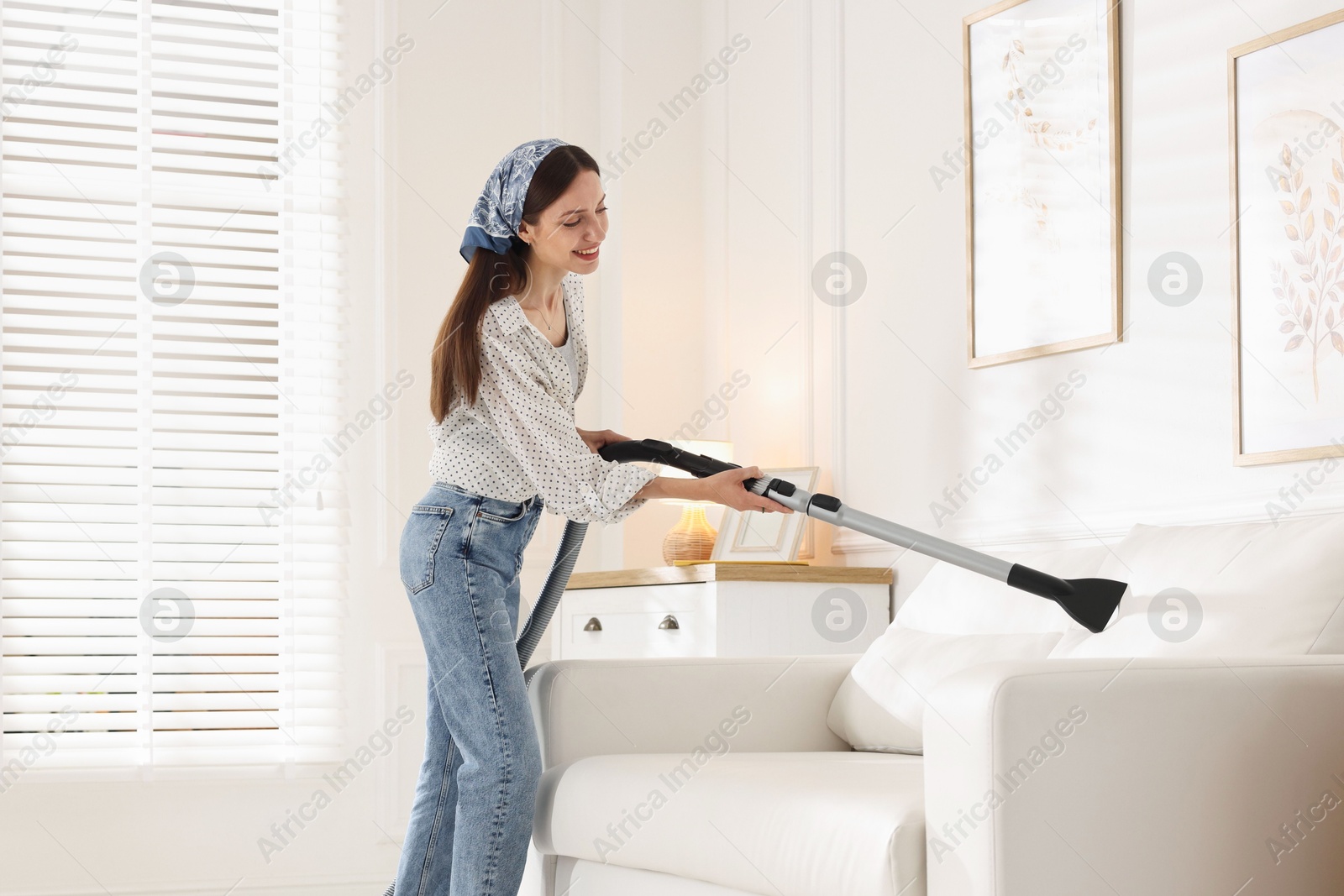Woman cleaning sofa with vacuum cleaner at home Photo of Woman cleaning sofa with vacuum cleaner at home
