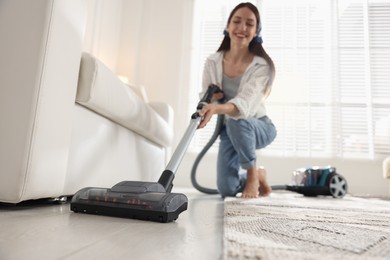 Photo of Woman cleaning floor with vacuum cleaner at home, low angle view