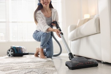 Photo of Woman cleaning floor with vacuum cleaner at home, low angle view