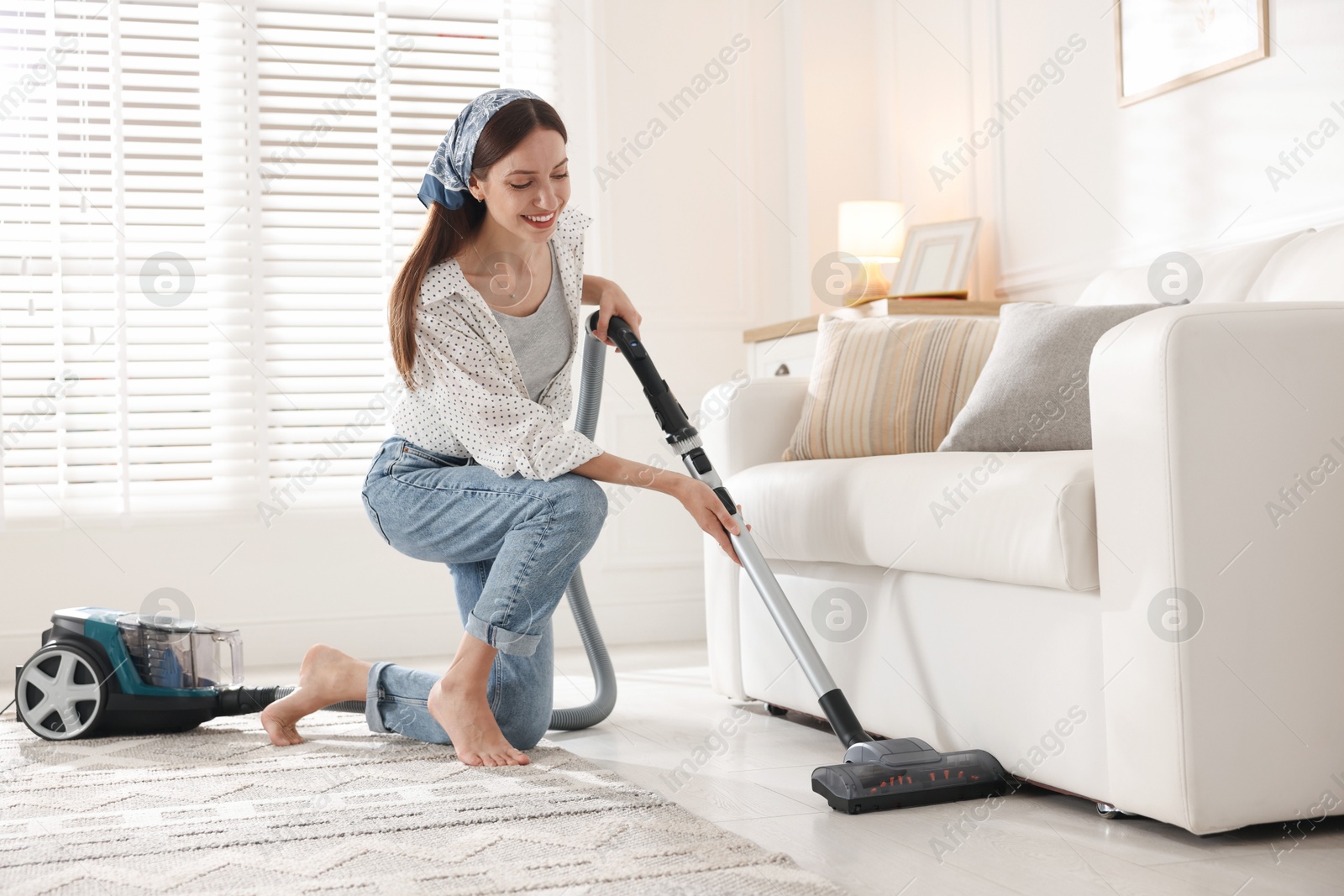 Woman cleaning floor with vacuum cleaner at home Photo of Woman cleaning floor with vacuum cleaner at home