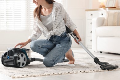 Photo of Woman cleaning carpet with vacuum cleaner at home, closeup