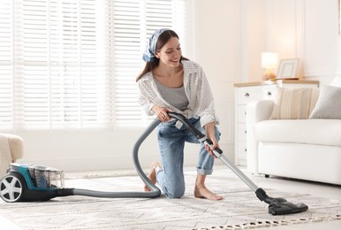 Photo of Woman cleaning carpet with vacuum cleaner at home