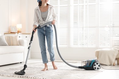 Photo of Woman cleaning carpet with vacuum cleaner at home, closeup
