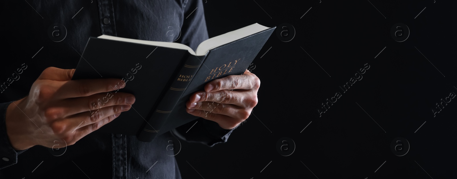 Photo of Priest with Holy Bible on black background, closeup. Space for text