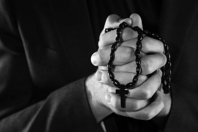 Photo of Priest with rosary praying, closeup. Black and white effect