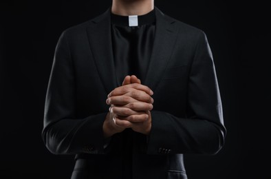 Photo of Priest praying on black background, closeup view