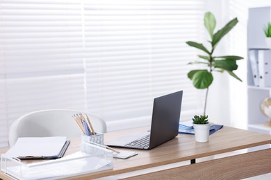 Photo of Doctor's workplace with modern laptop on desk in office