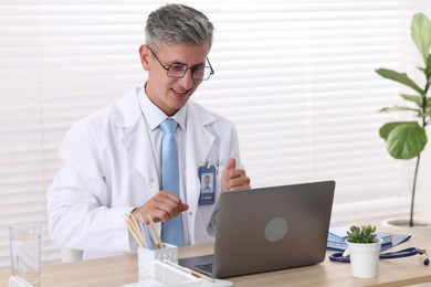 Photo of Telemedicine. Doctor having video call with patient via laptop indoors